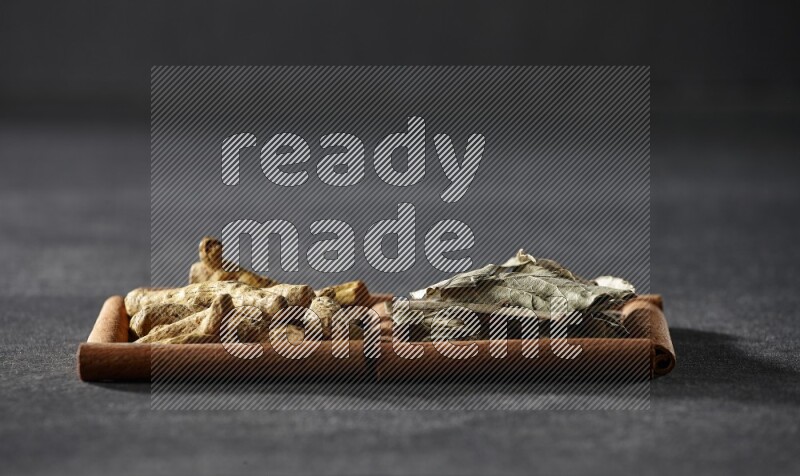 2 squares of cinnamon sticks full of bay laurel leaves and turmeric fingers on black flooring