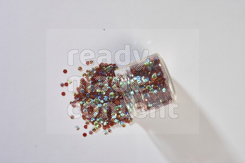 Colored flat sequins in a glass jar on grey background