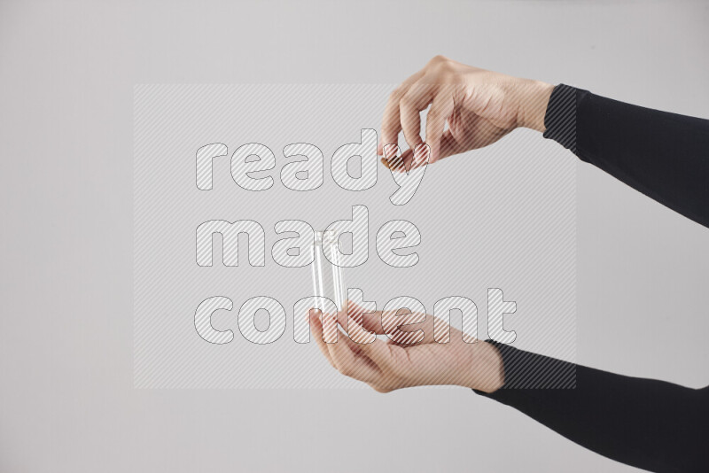 A woman in black abaya holding different glassware in different positions