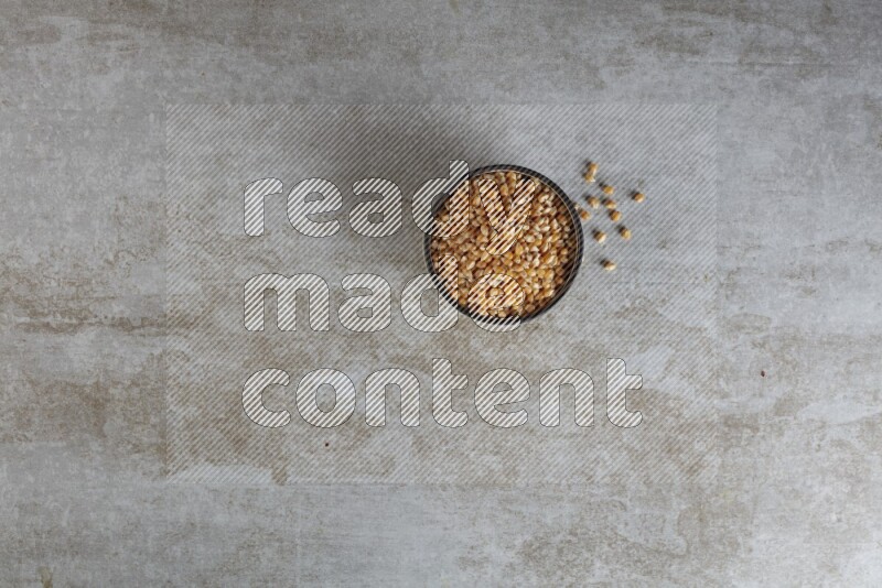 corn kernel in multi-colored pottery bowl on a grey textured countertop