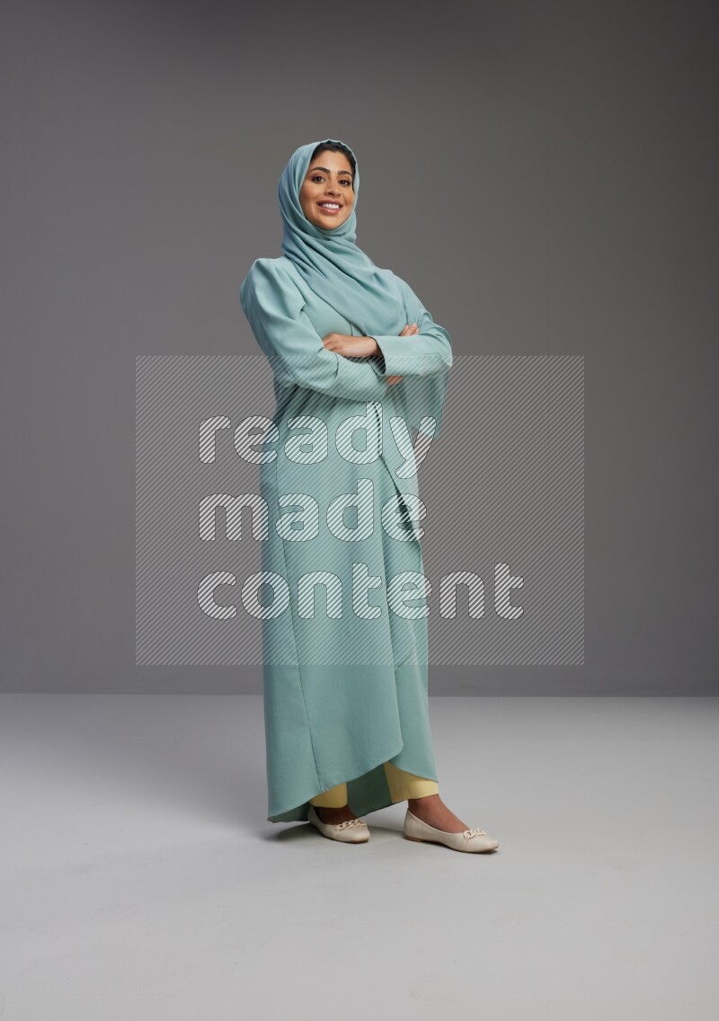 Saudi Woman wearing Abaya standing with crossed arms on Gray background