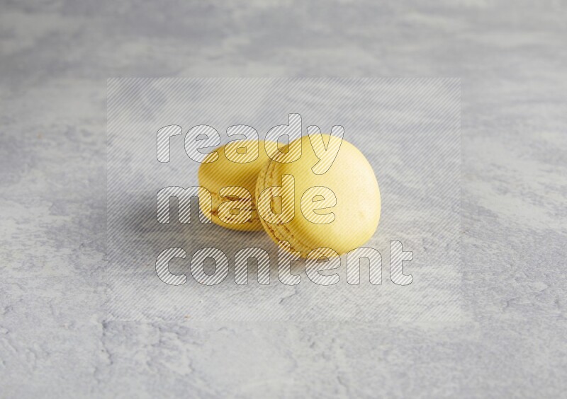 45º Shot of two Yellow Lemon macarons  on white  marble background