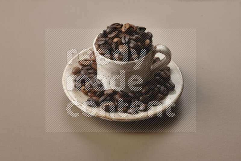 A beige pottery cup full of roasted coffee beans on beige background