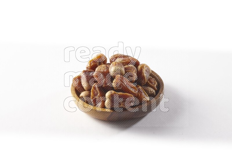 Dates in a wooden bowl on white background