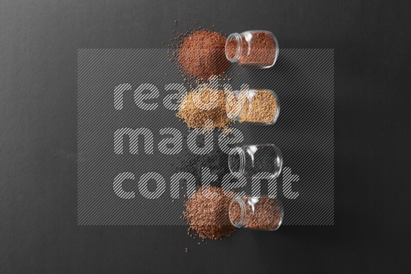 حبة البركة و حبوب الخردل وحبوب الكتان وحب الرشاد في أوعية زجاجية علي خلفية سوداء