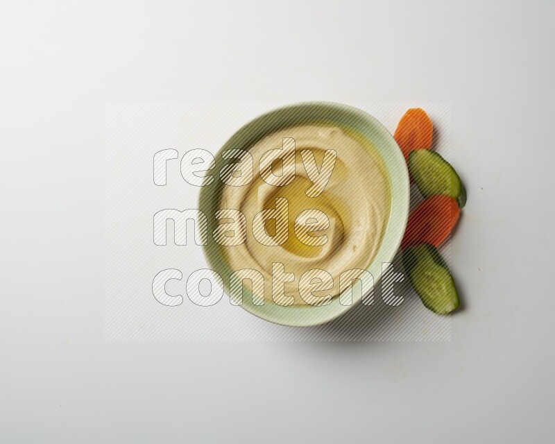 Hummus in a green plate garnished with olive oil on a white background