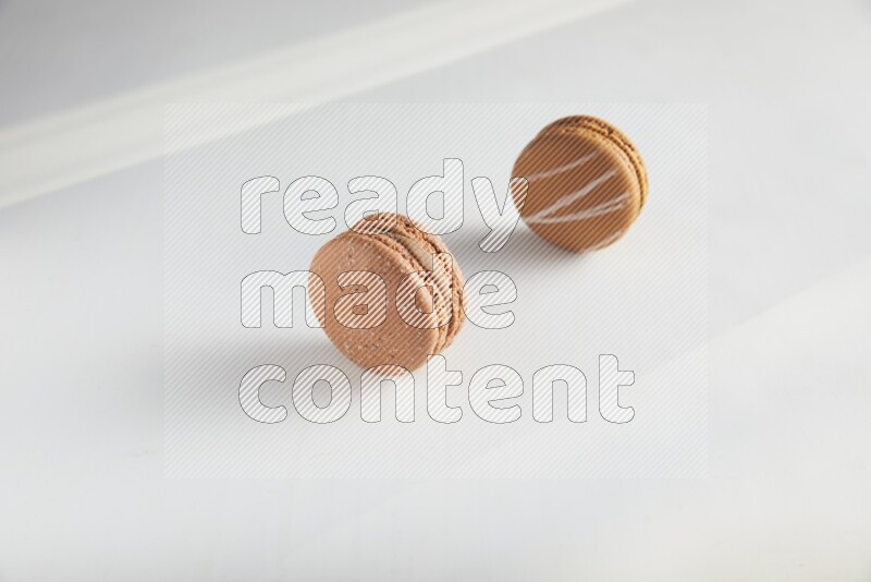 45º Shot of of two assorted Brown Irish Cream, and Brown Hazelnuts macarons on white background