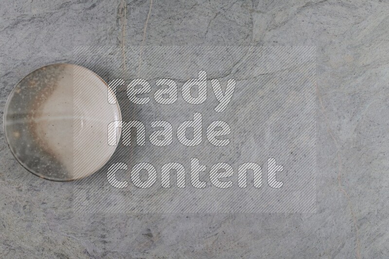 A multicolored pottery plate on grey marble background