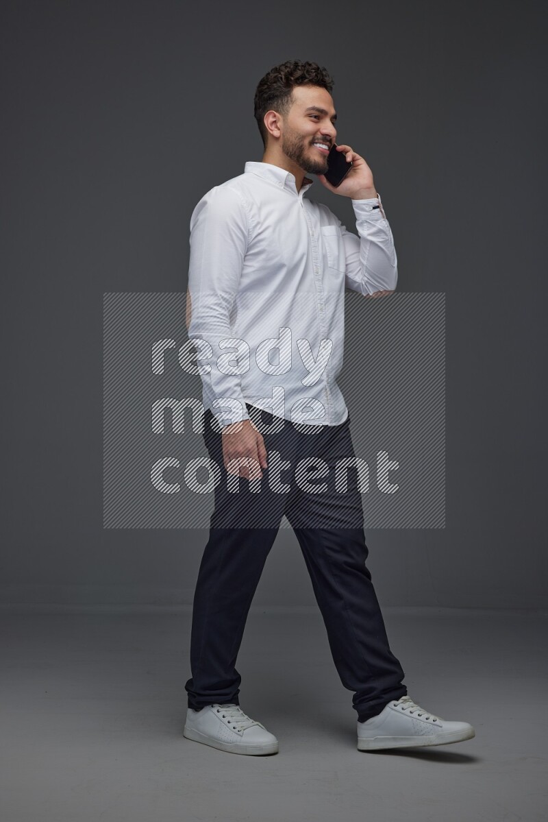 A man wearing smart casual talking in the phone eye level on a gray background