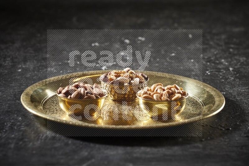 Nuts in metal bowls on a tray in a dark setup