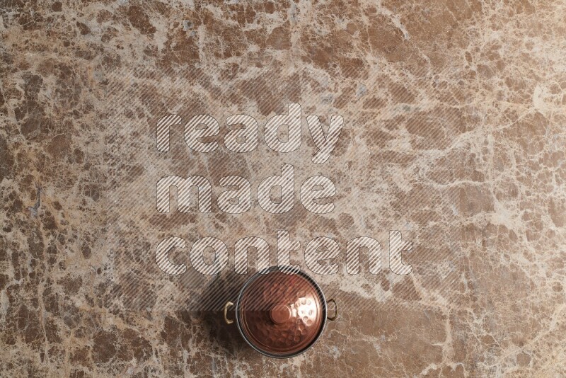 A small copper pot on beige marble background