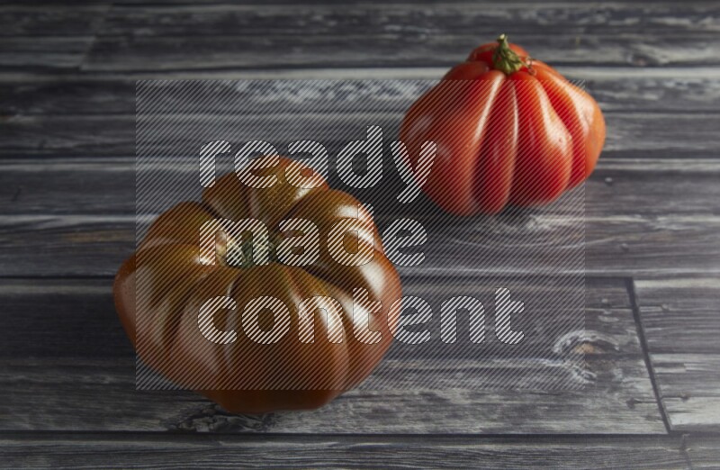 45 degree two heirloom tomato on a textured grey wooden background