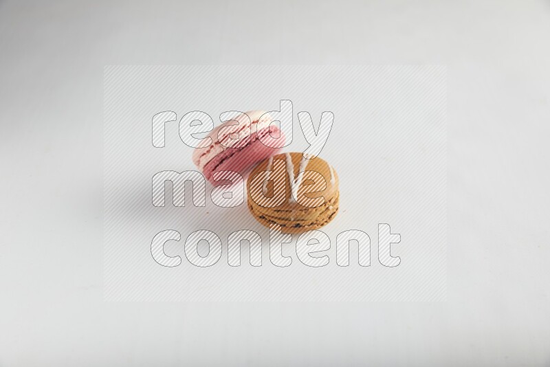 45º Shot of of two assorted Brown Irish Cream, and Pink Litchi Raspberry macarons on white background