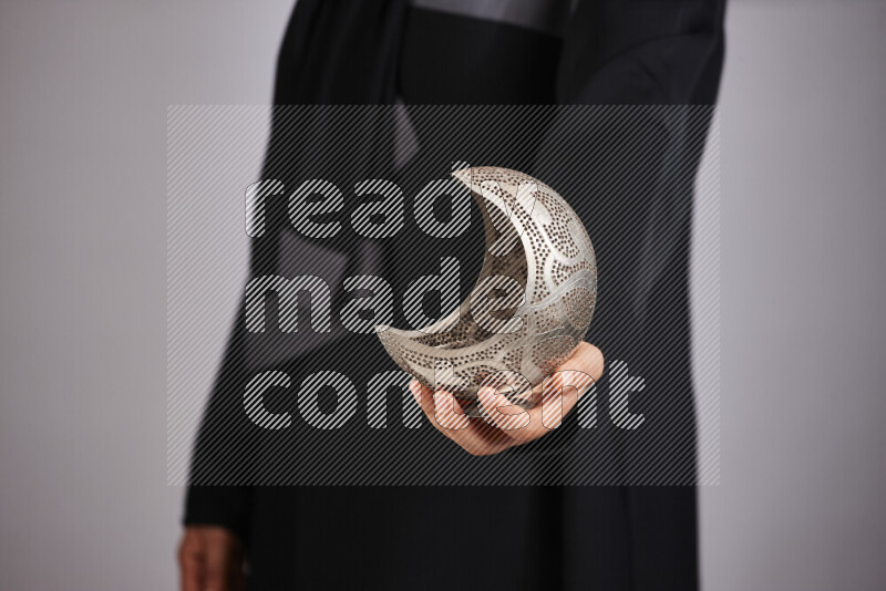 A woman in black abaya holding different ramadan lanterns in different positions