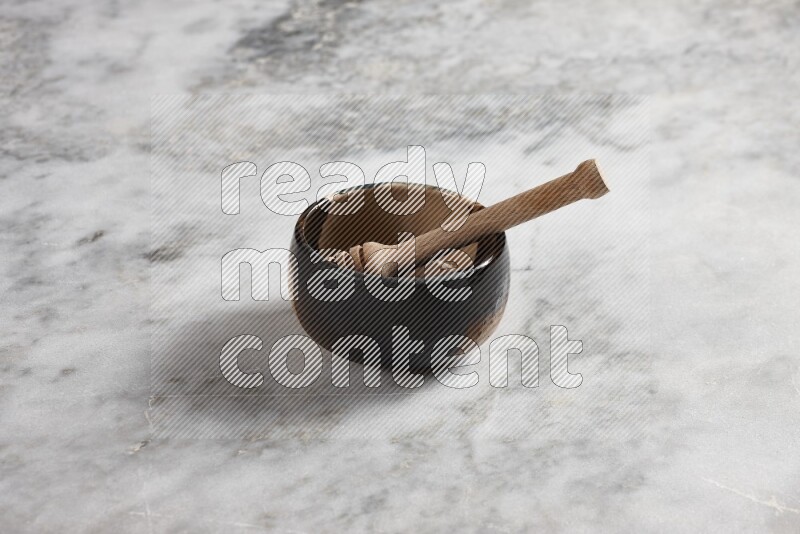 Multicolored pottery bowl with wooden honey dipper in it on grey marble background