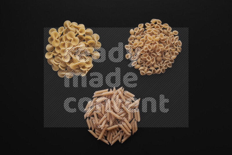 Different pasta types in bunches on black background