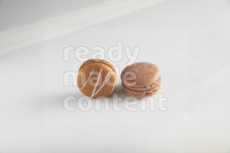 45º Shot of of two assorted Brown Irish Cream, and Brown Hazelnuts macarons on white background