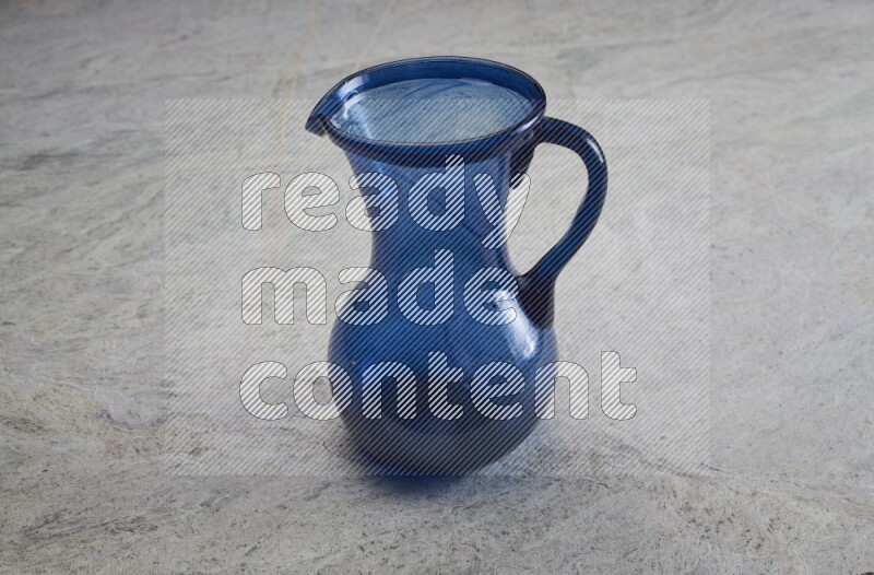 A colored glass jug on grey marble background