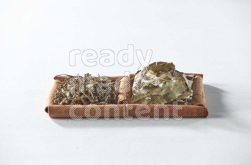 2 squares of cinnamon sticks full of dried basil and bay laurel leaves on white flooring