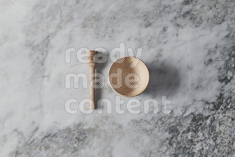 Multicolored pottery bowl with wooden honey dipper on the side on grey marble background