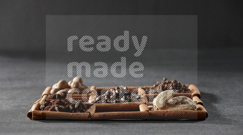 9 مربعات من أعواد القرفة ممتلئة بحبوب القهوة في المنتصف محاطة بجوزة الطيب والنعناع المجفف والقرنفل والريحان المجفف والزنجبيل المجفف والقرفة واليانسون والهيل على أرضية سوداء