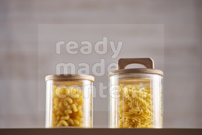 Raw pasta in glass jars on beige background