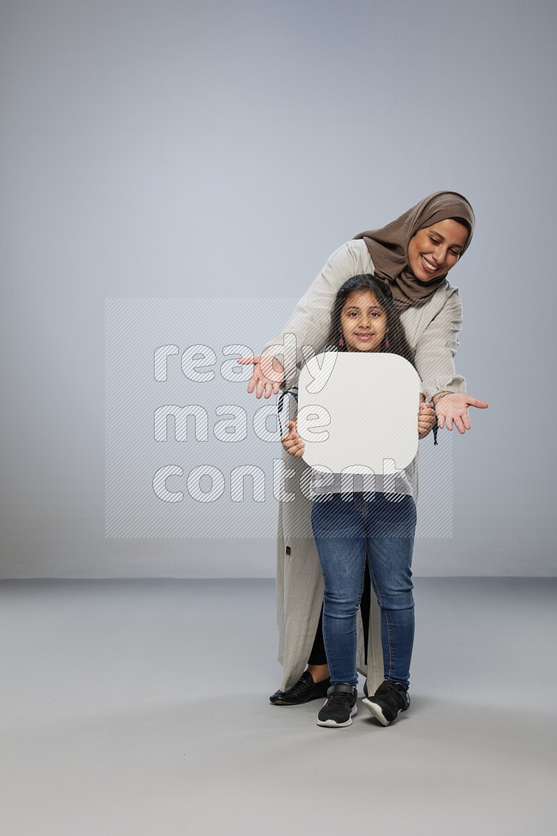 Mom and daughter standing holding social media sign on gray background