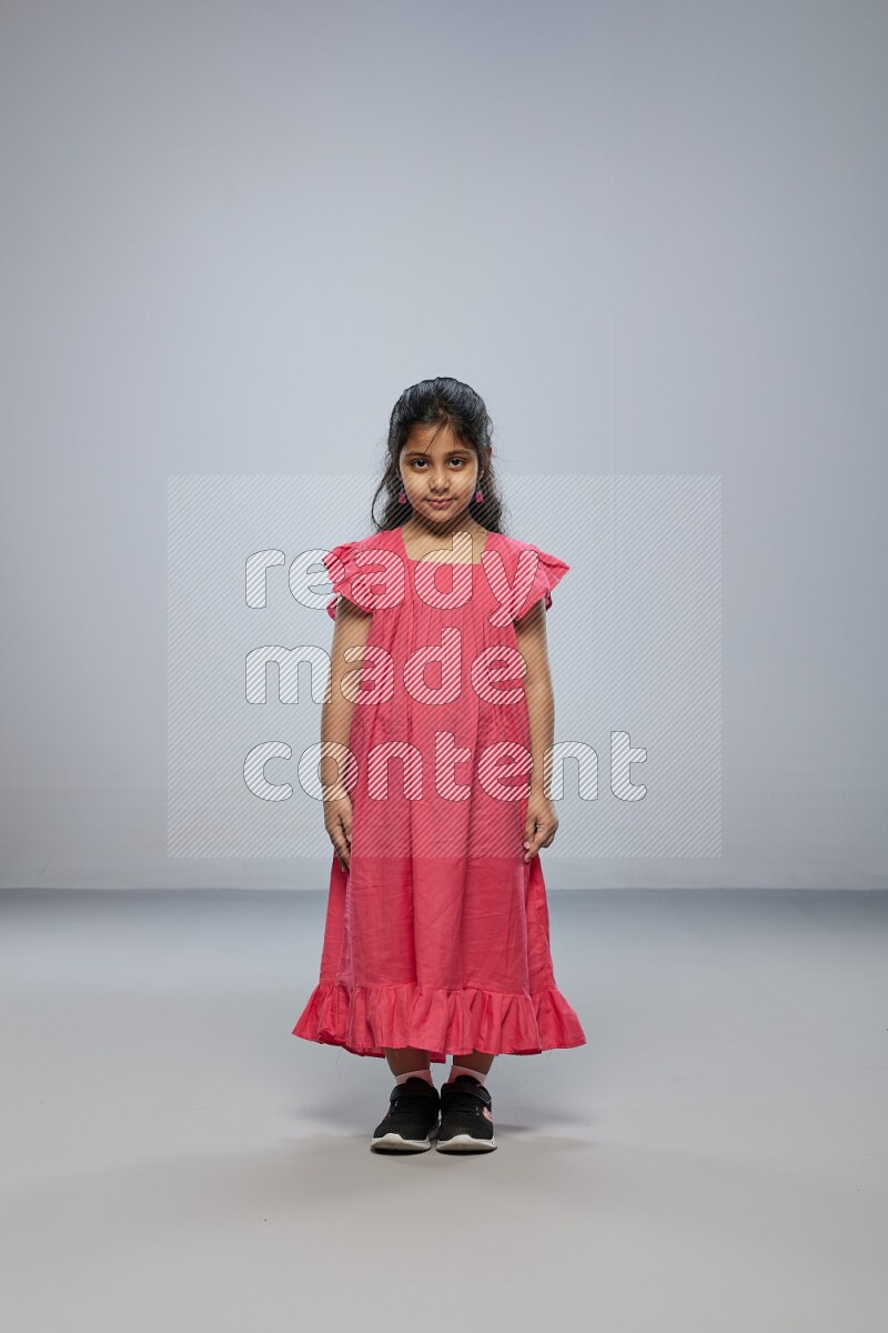 A girl standing interacting with the camera on gray background