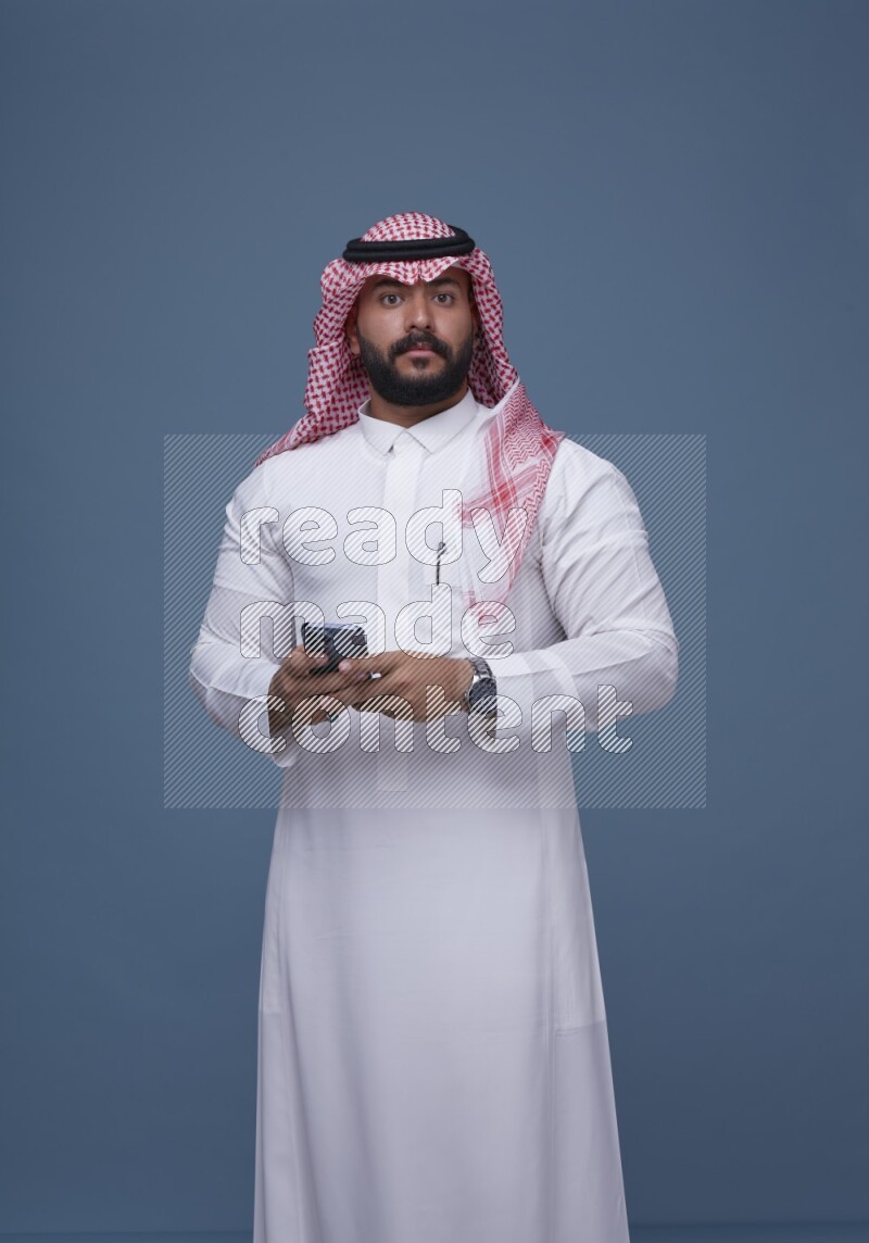 A man Texting on Blue Background wearing Saudi Thob and Shomag