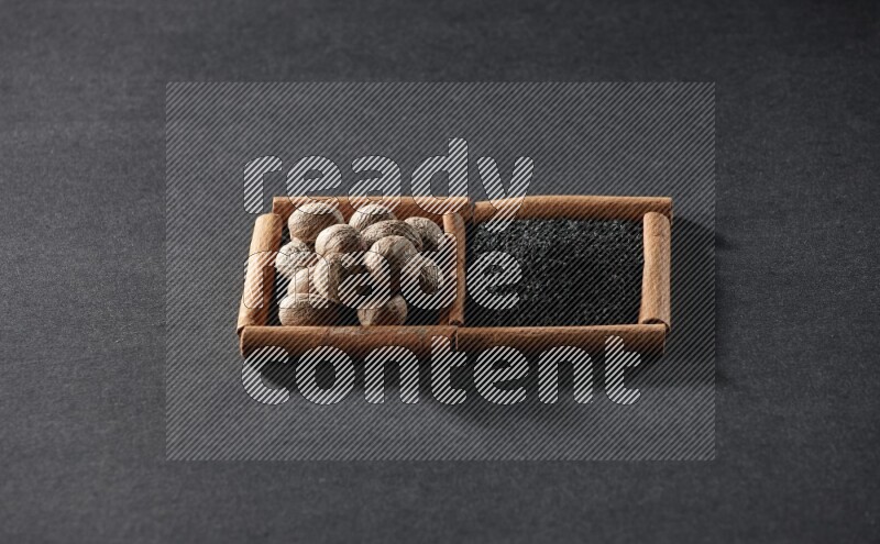 2 squares of cinnamon sticks full of black seeds and nutmeg on black flooring