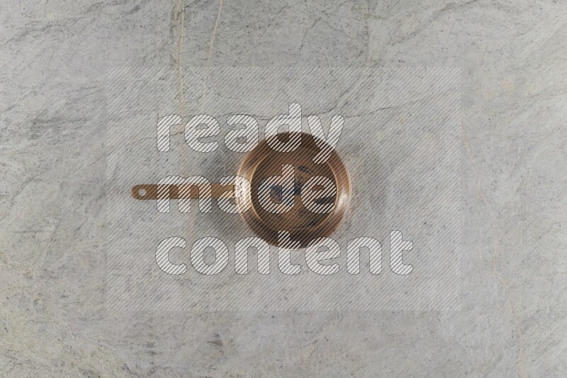 A small copper pan on grey marble background