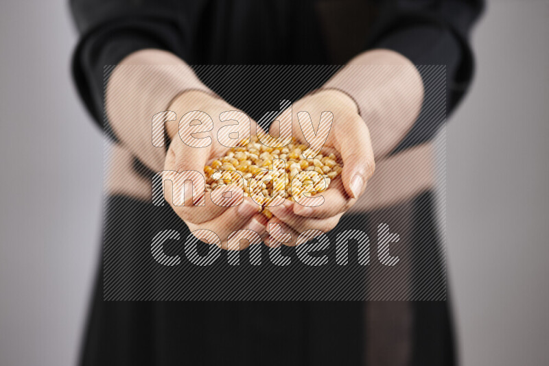 Woman in abaya holding different kinds of legumes in different positions