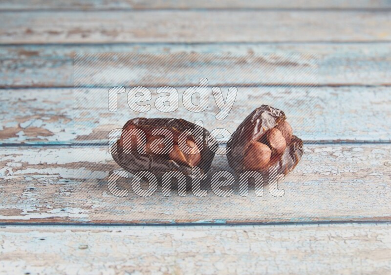 two hazelnuts stuffed madjoul dates on a light blue wooden background