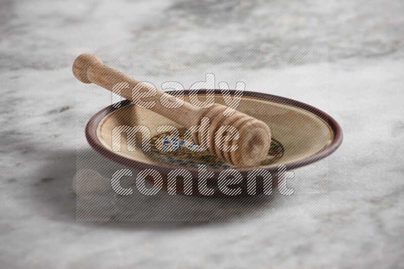 Decorative pottery plate with wooden honey dipper in it on grey marble background