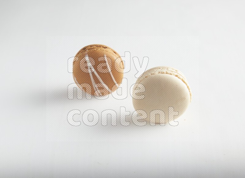45º Shot of of two assorted Brown Irish Cream, and White Caramel fleur de sel macarons on white background