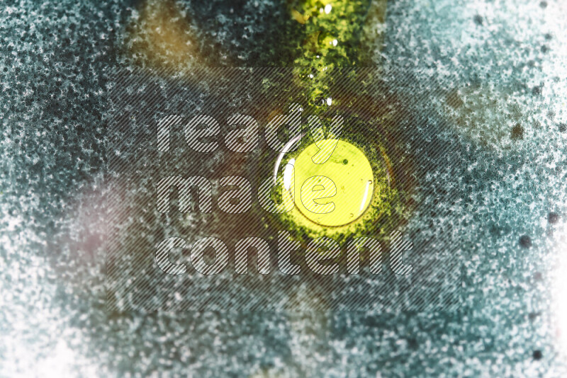 لقطات مقربة لقطرات ألوان مائية خضراء وصفراء على سطح الزيت على خلفية بيضاء