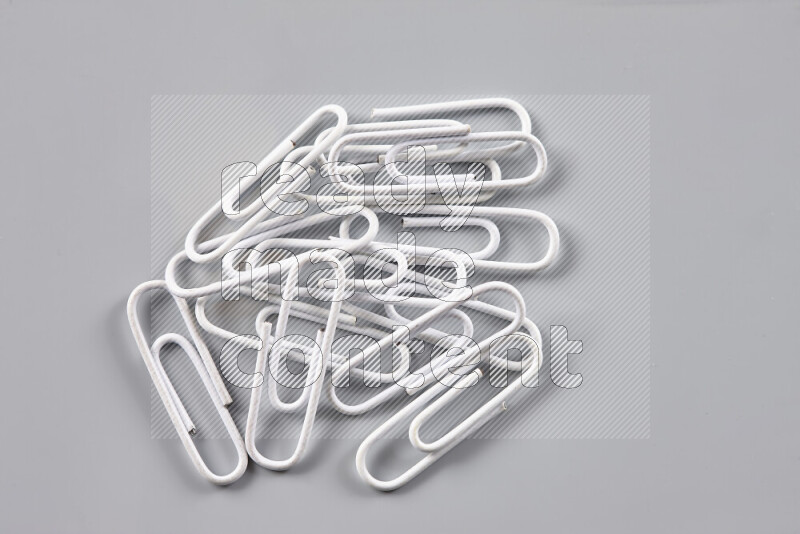 White paper clips isolated on a grey background