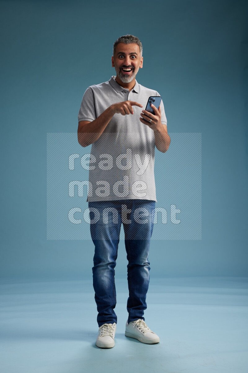 Man Standing texting on phone on blue background