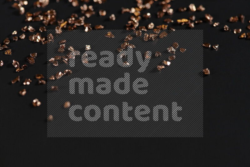 Bronze shimmering fragments of glass scattered on a black background