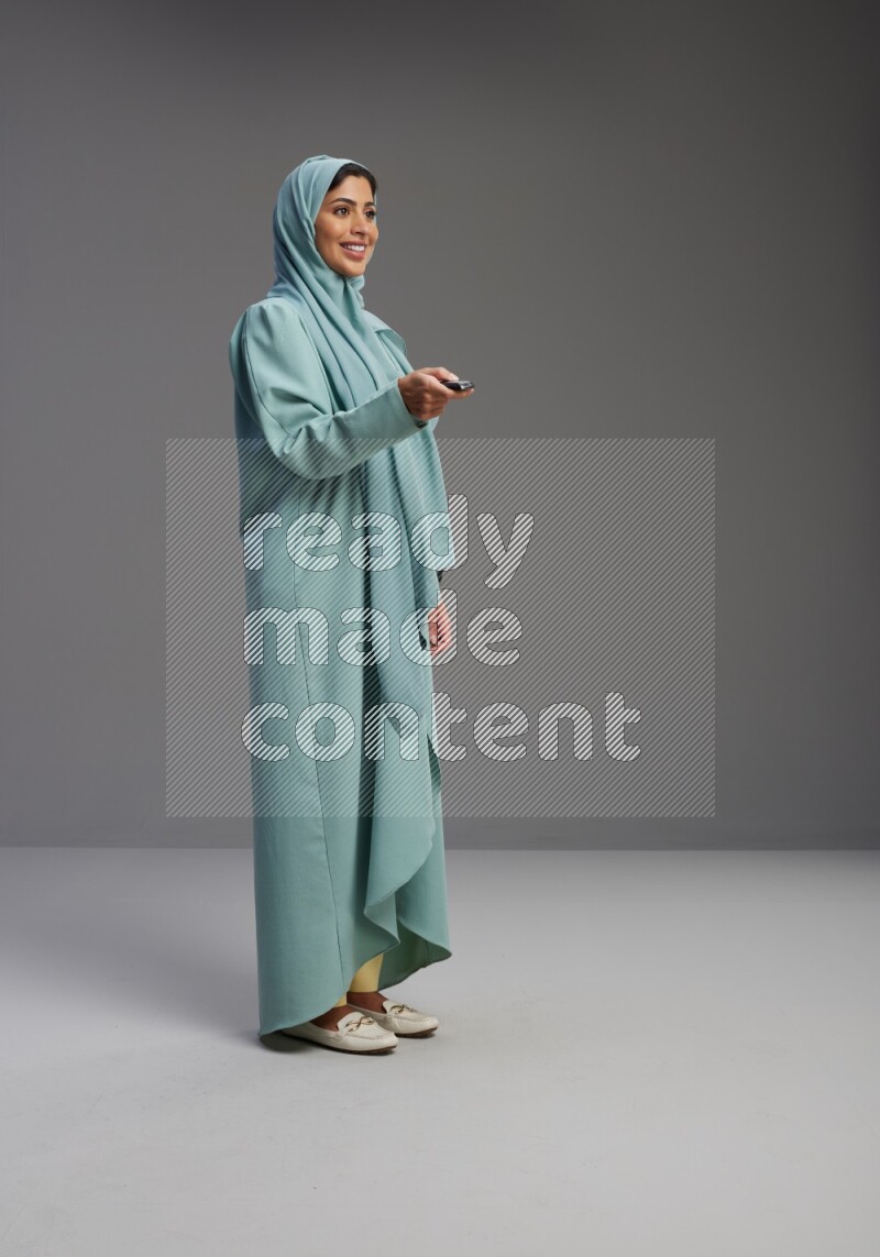 Saudi Woman wearing Abaya standing holding car key on Gray background