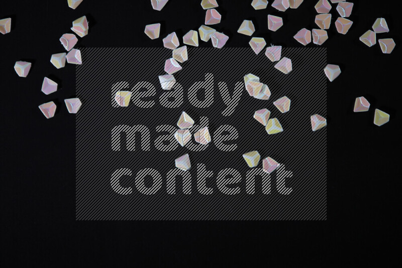 Colorful plastic shards for decoration scattered on a black background