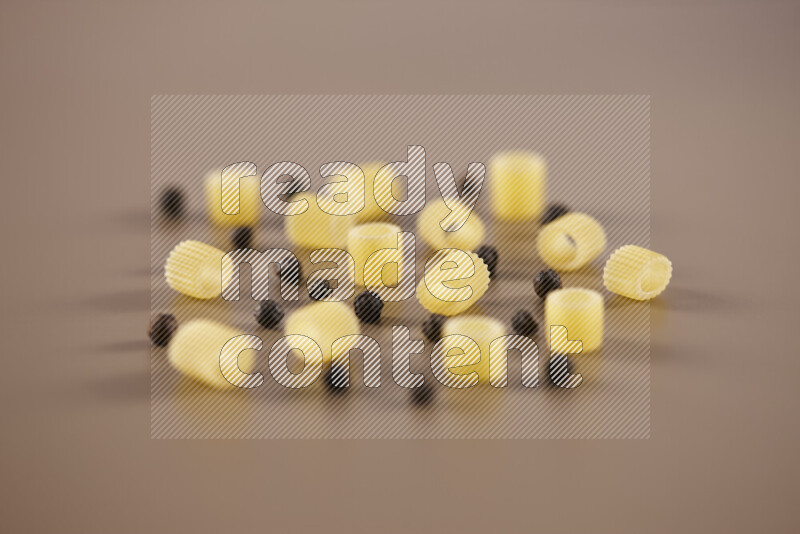 معكرونة مع مكونات متنوعة من الطماطم والثوم والبصل والفلفل الأحمر والفلفل الأسود والفلفل الأبيض وأوراق الغار وإكليل الجبل والهيل على خلفية بيج