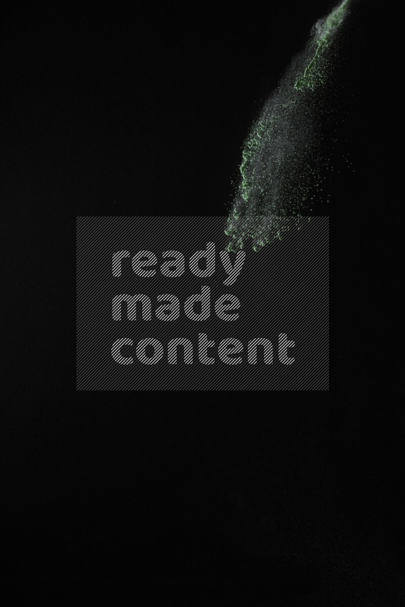 A side view of green powder explosion on black background