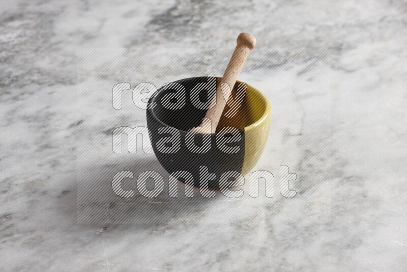 Multicolored pottery bowl with wooden honey dipper in it on grey marble background