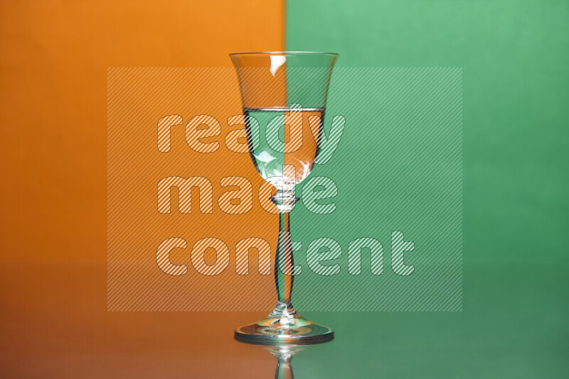 The image features a clear glassware filled with water, set against orange and green background