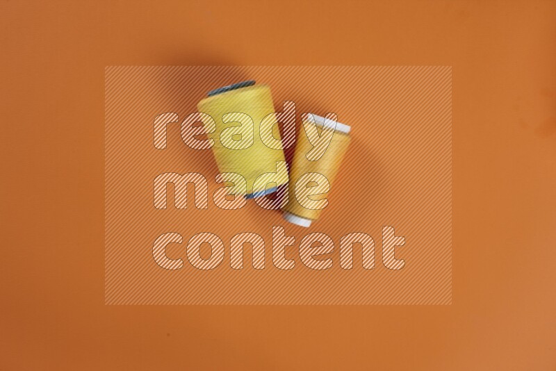 A yellow collection of sewing and tailoring tools arranged on a orange background