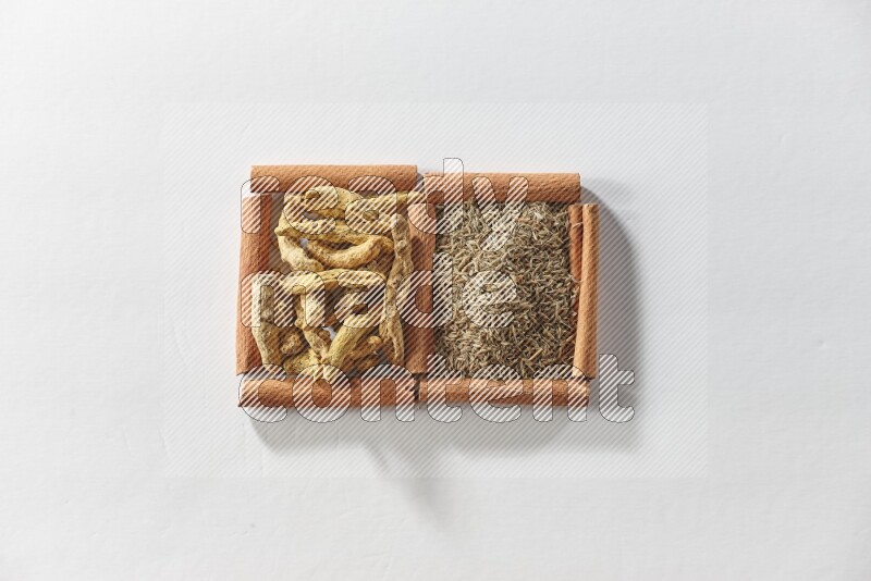 2 squares of cinnamon sticks full of cumin and turmeric fingers on white flooring