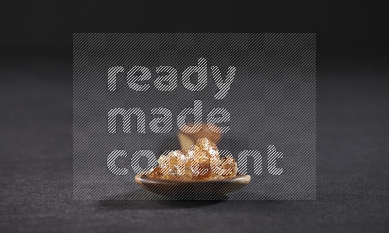 ملعقة خشبية كبيرة ممتلئة بقطع الصمغ العربي علي خلفية سوداء