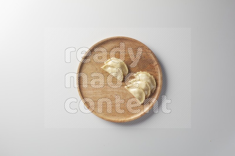 Five Sambosas on a wooden round plate on a white background