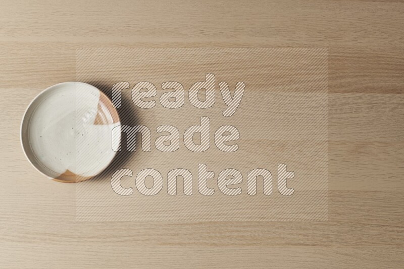 A multicolored pottery plate on light wooden background